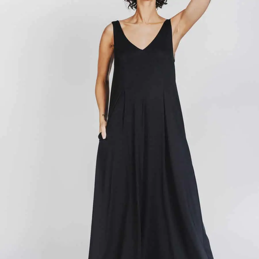 Deep White Black Modell SASHA langes Kleid schwarz mit schwarzen Fellsandalen aus Holz von Devich, ärmelloses Sommerkleid mit V-Ausschnitt, Ansicht gesamt von vorne