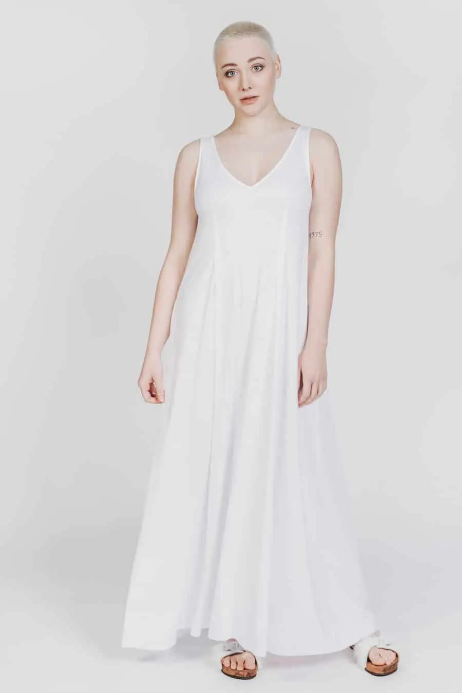 Deep White Black Modell SASHA langes Kleid weiß mit weißen Fellsandalen aus Holz von Devich, ärmelloses Sommerkleid mit V-Ausschnitt, Ansicht gesamt von vorne