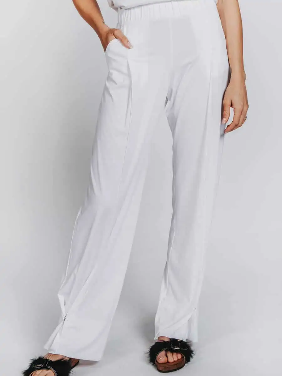 Deep White Black Modell ZOE weite Damen Hose weiß mit Bügelfalte, Damen Stoffhose aus Viscose mit elastischem Bund, Druckknopf geschlossen, schwarze Fellsandalen aus Holz von Devich, Ansicht von vorne